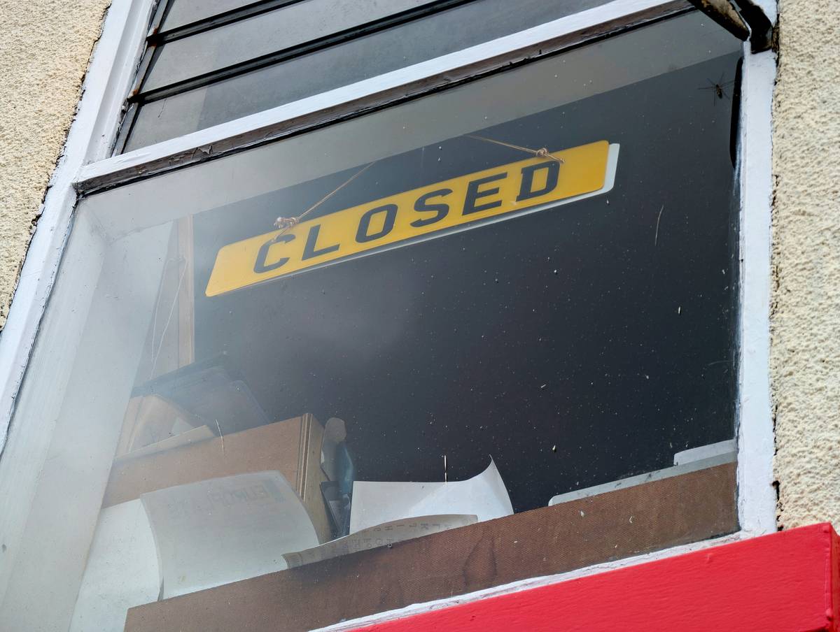 Yellow CLOSED sign hanging in a dusty shop window, conveying themes of business failure, recession, and economic downturn
